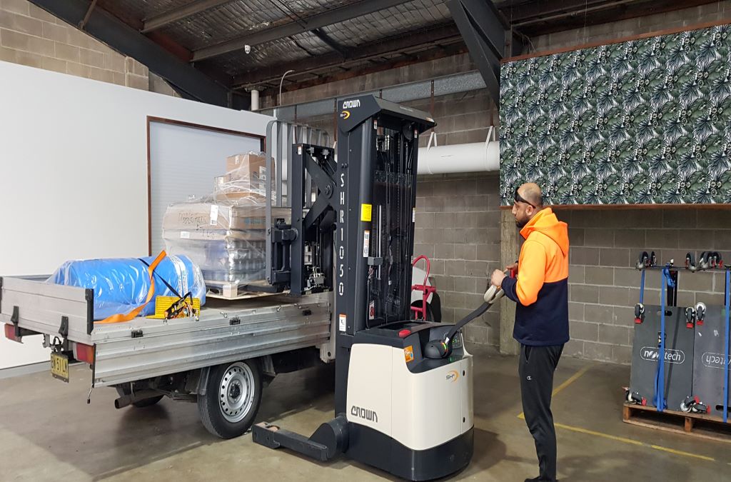 man pushing a forlift with wrapped packages